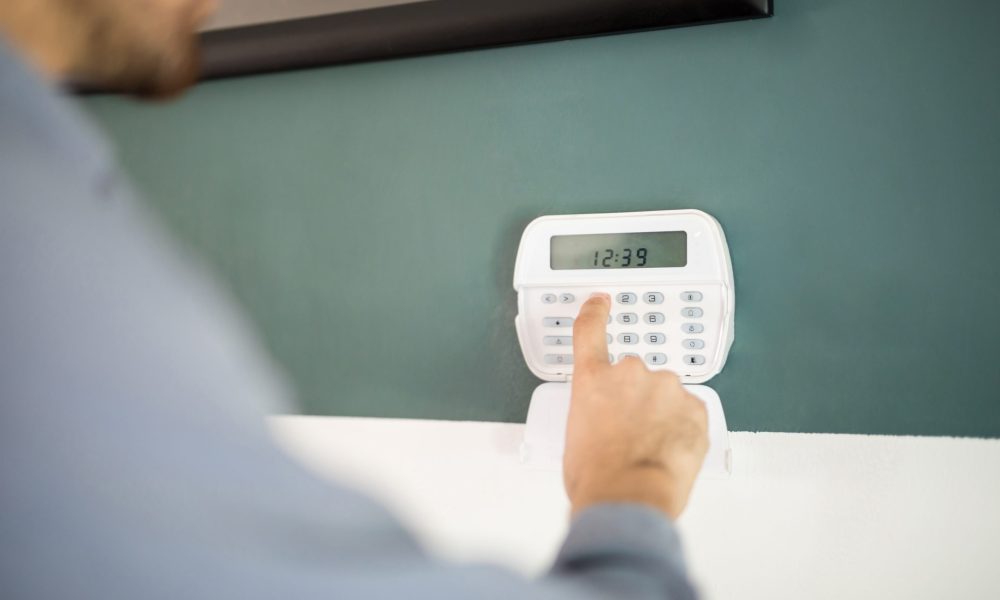 Closeup of the hand of a man using a keypad to arm his home alarm system