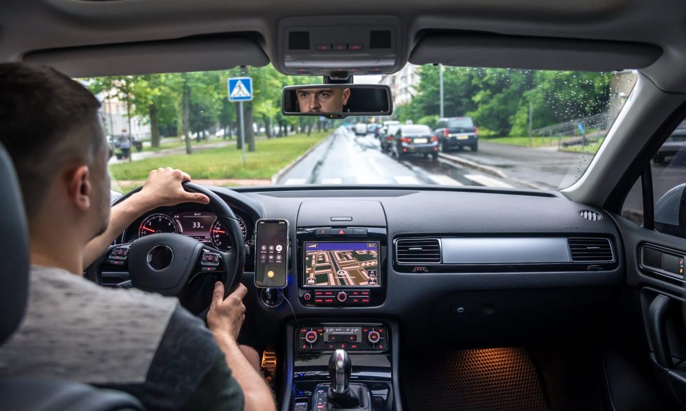 A male driver drives at the streets of the city, a view from inside the car.