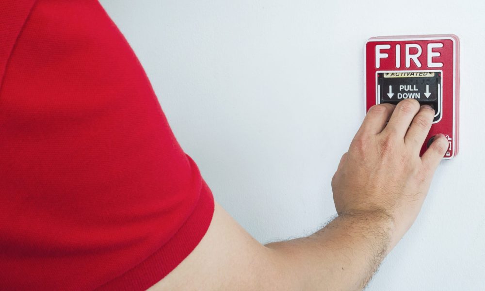 Man is reaching his hand to push fire alarm hand station